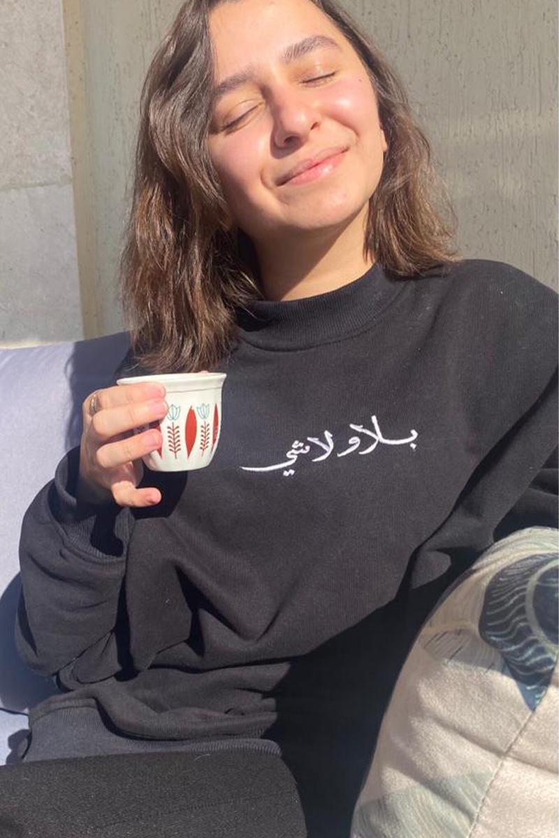 black sweatshirt hand-embroidered with lyrics fron Ziad Rahbani's song meaning without anything